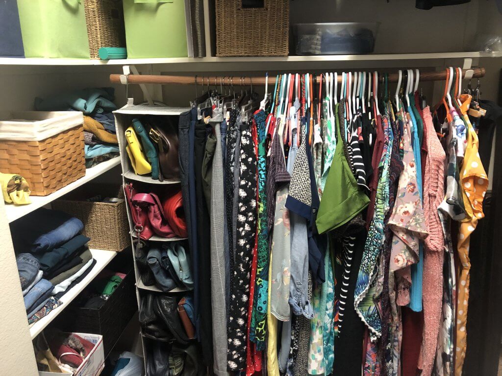 Part of my closet after the cleanse, showing my dresses and hanging organizer holding purses.